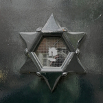 Zeshoekig deurraam omgeven door ster.
<br/>
Corrie Groen- Pickhard, 2014-04-17